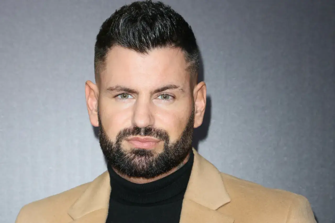 Wojtek Gola, wiek nieznany, z brodą i w beżowym płaszczu.