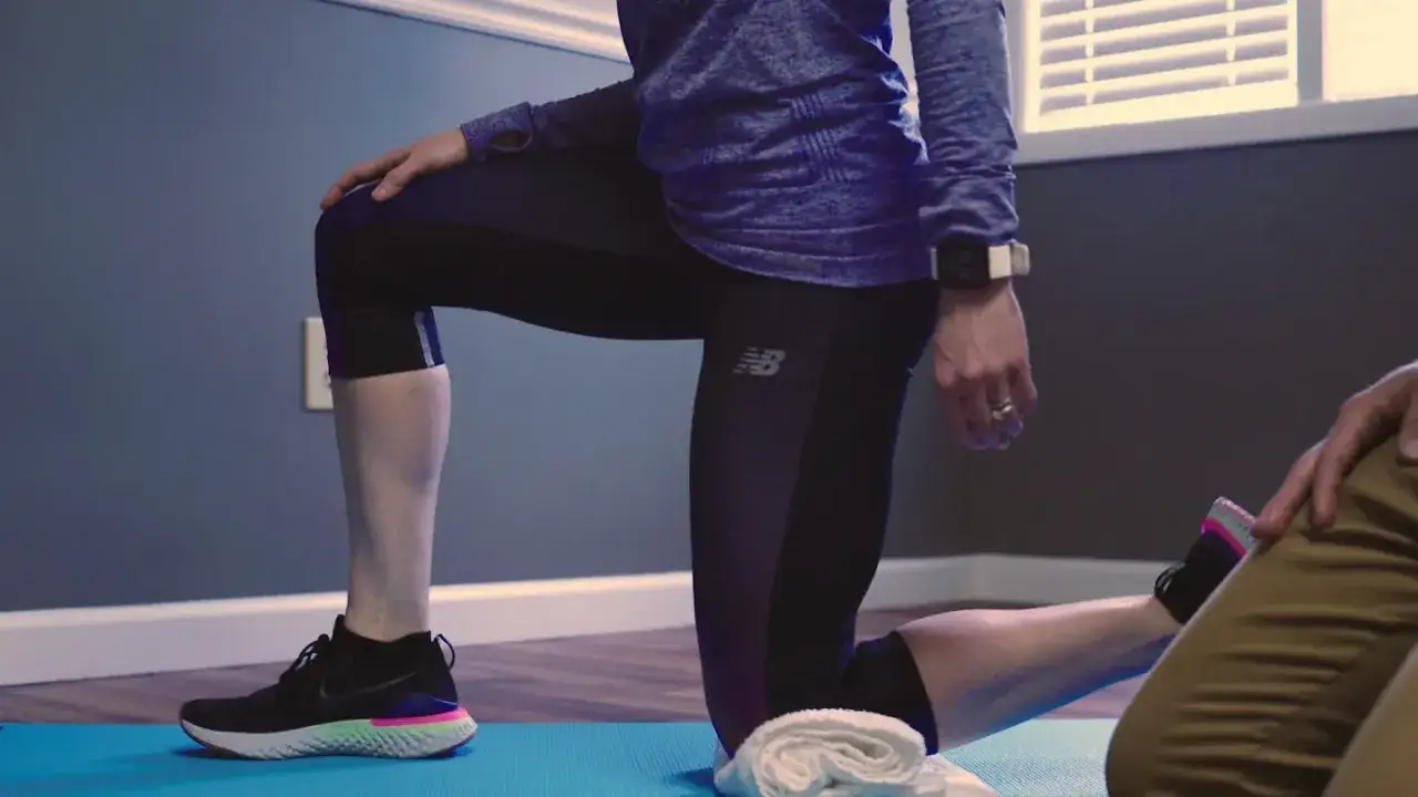 Kobieta na macie ćwiczy, przygotowując się do biegania. Pokazuje, jak nauczyć się biegać, rozciągając mięśnie.