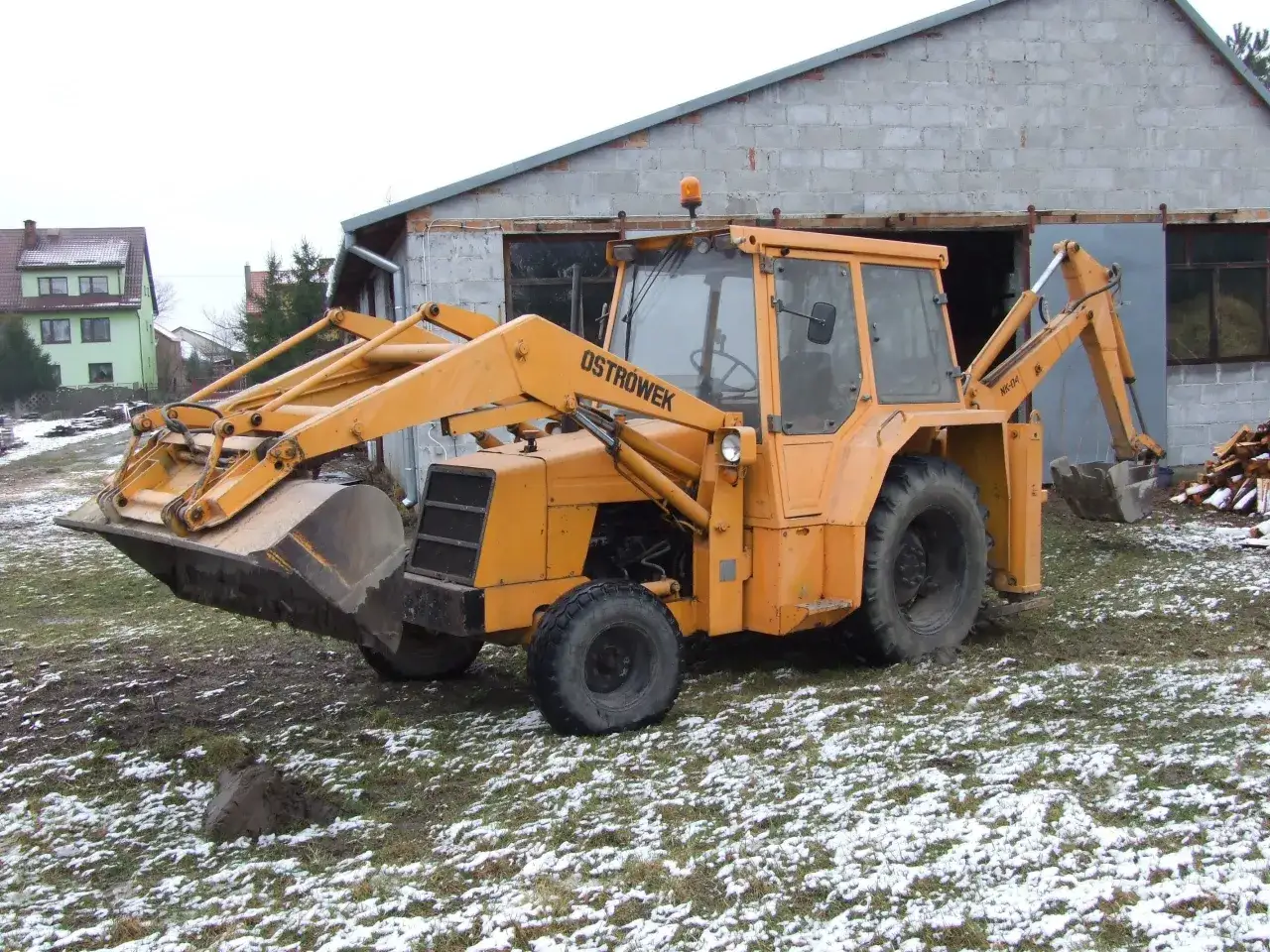 Żółta koparko-ładowarka Ostrówek NK-04, gotowa do pracy. Ile waży koparka ostrówek? To potężna maszyna budowlana.