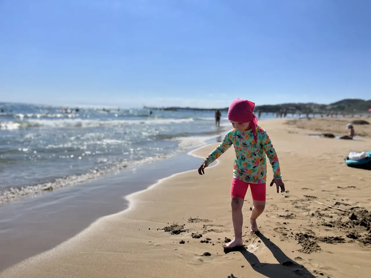 Dziecko bawi się na plaży, fale obmywają brzeg. Czy riwiera turecka jest bezpieczna? Wygląda na to, że tak, bo wakacje trwają w najlepsze.