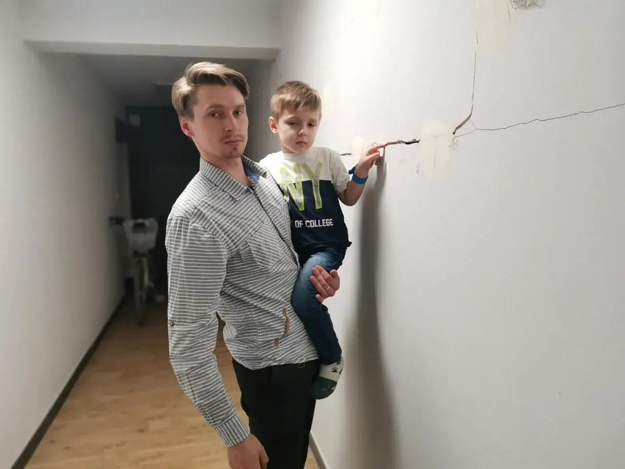 Ojciec z synem wskazują na pęknięcia ścian, problem odpowiedzialności dewelopera za wady budowlane.