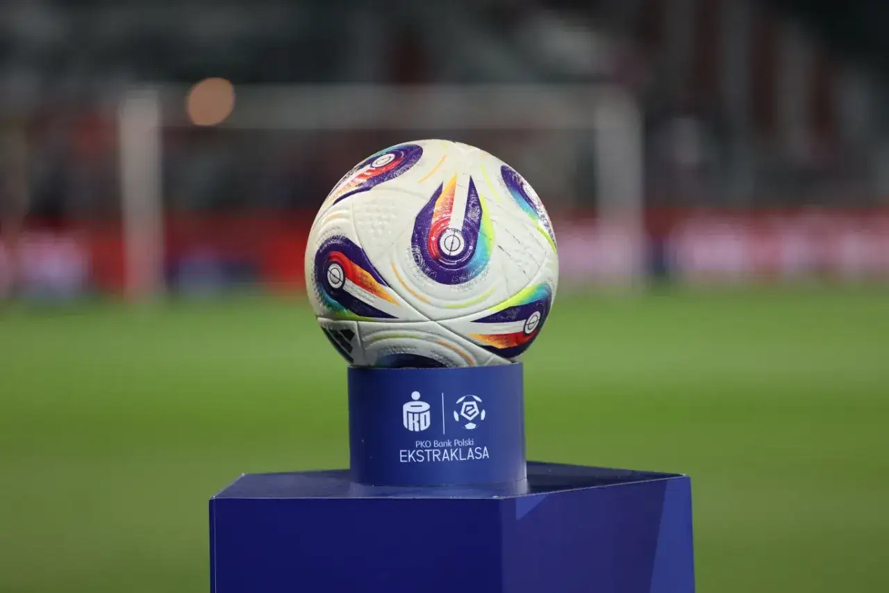 Piłka do piłki nożnej na niebieskim postumencie z logo PKO Bank Polski Ekstraklasa. Czekamy, kiedy terminarz ekstraklasy przyniesie emocje.