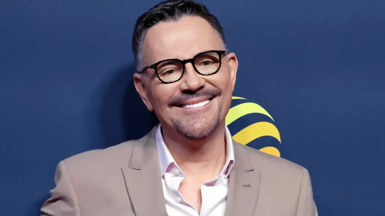 Uśmiechnięty Krzysztof Ibisz w beżowej marynarce i okularach. Ciekawe, ile lat ma Krzysztof Ibisz, bo wygląda świetnie!