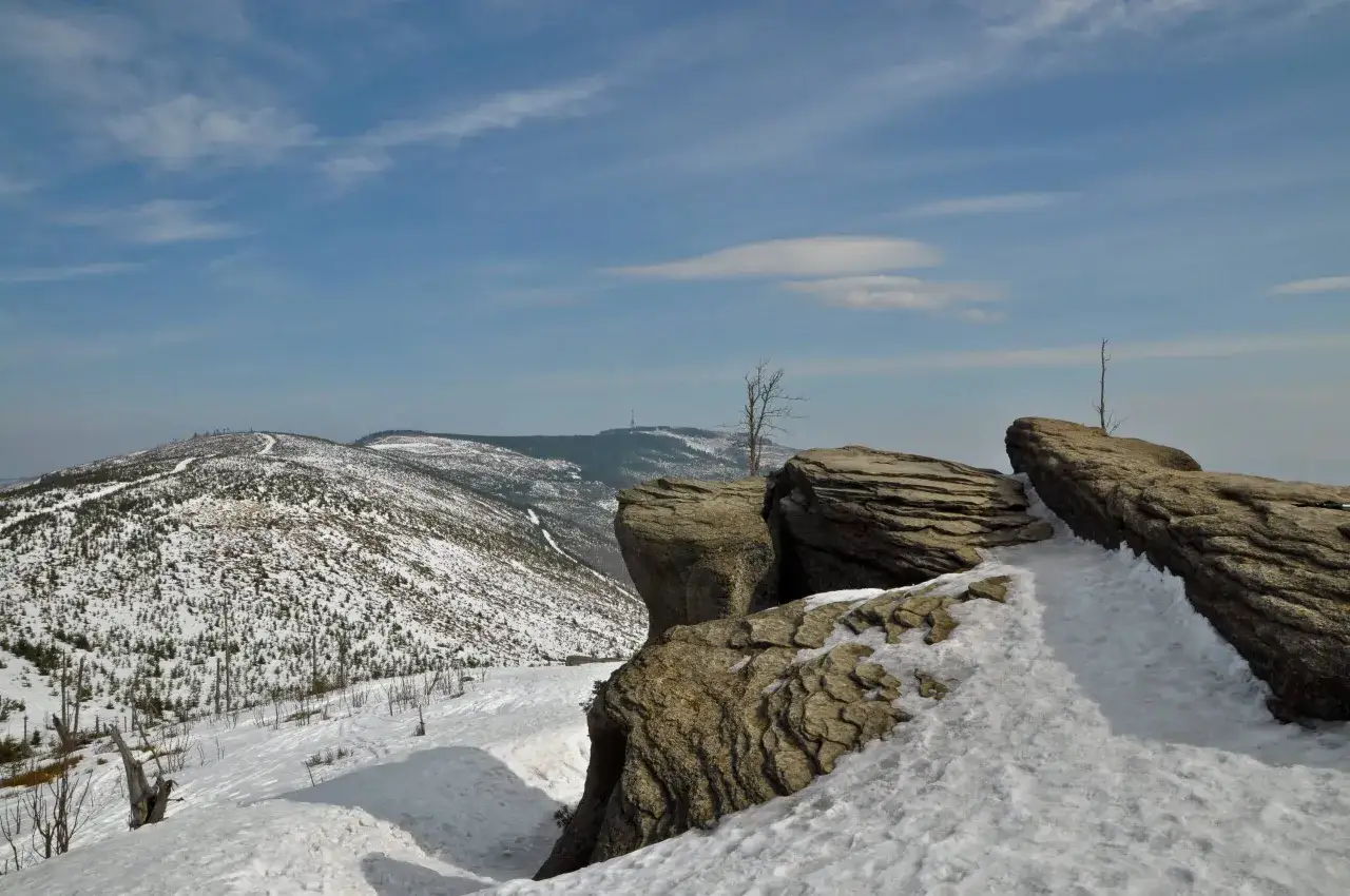 Skaliste urwisko i ośnieżony szlak na Skrzyczne. W oddali widać kolejne szczyty Beskid&oacute;w.
