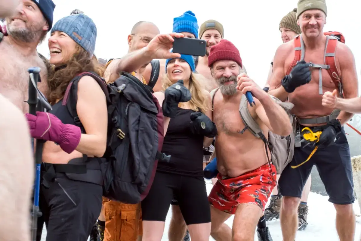 Grupa ludzi w czapkach i rękawiczkach, niektórzy bez koszulek, pozuje do selfie. To może być część praktyki medytacji Wima Hofa.
