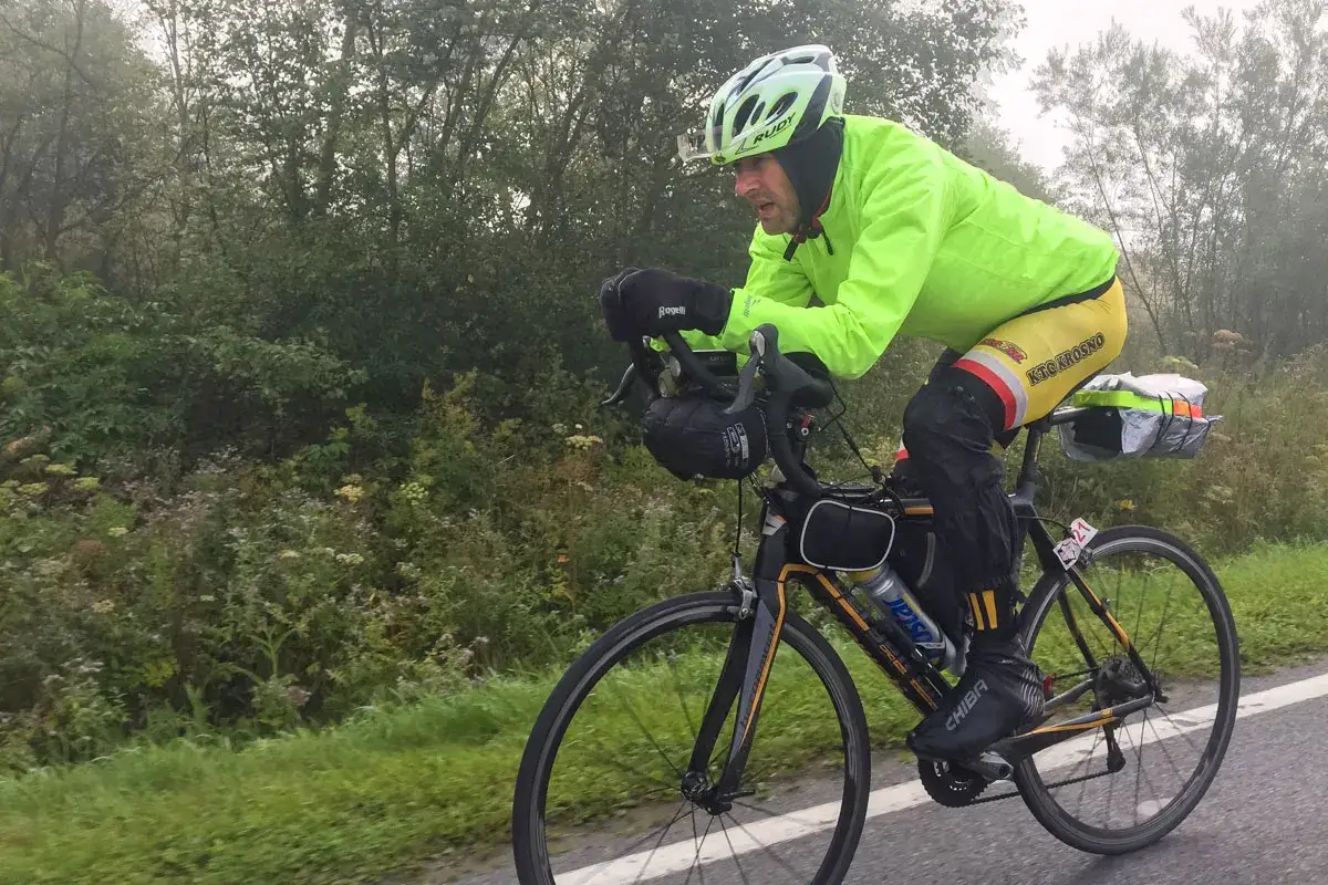 Kolarz w jaskrawej kurtce i kasku pokonuje dystans podczas maratonu rowerowego.