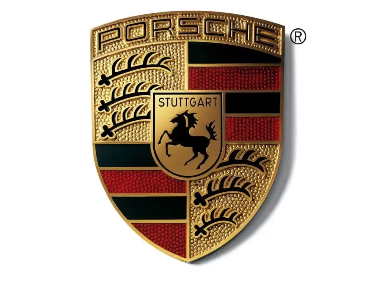Złote logo Porsche, symbol luksusowych marek samochod&oacute;w, z herbem Stuttgartu i czarnym koniem.