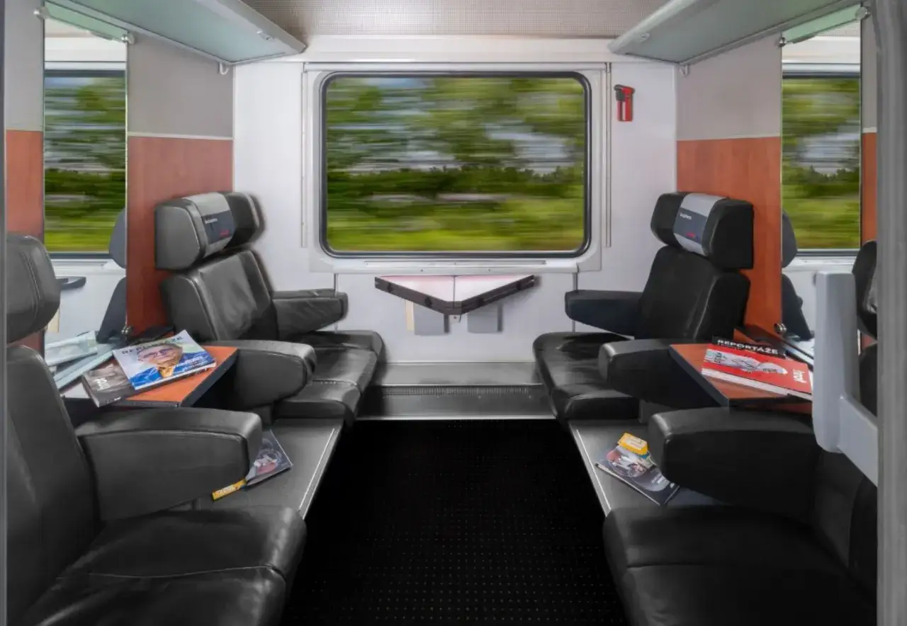 Wnętrze wagonu kolejowego z wygodnymi fotelami i widokiem na rozmyty krajobraz. Zastanawiasz się, ile jest kilometrów z Poznania do Krakowa?