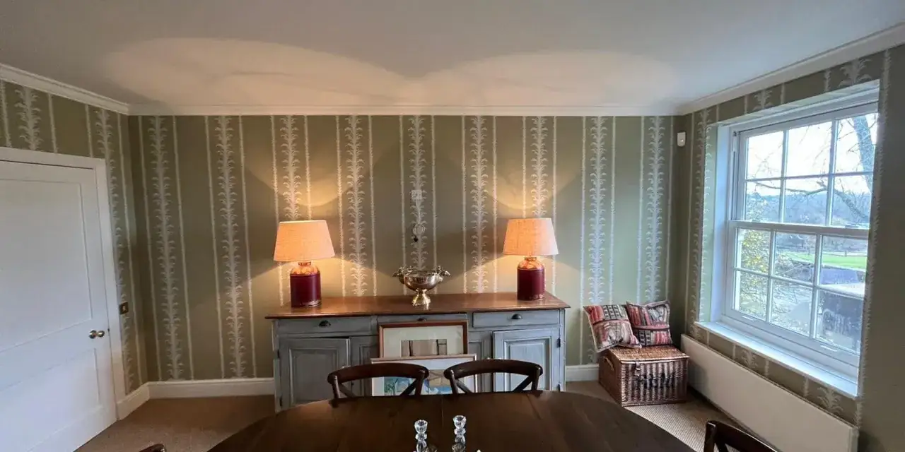 Eleganckie tapetowanie przy otworach okiennych i drzwiowych, z subtelnym wzorem roślinnym na zielonym tle.