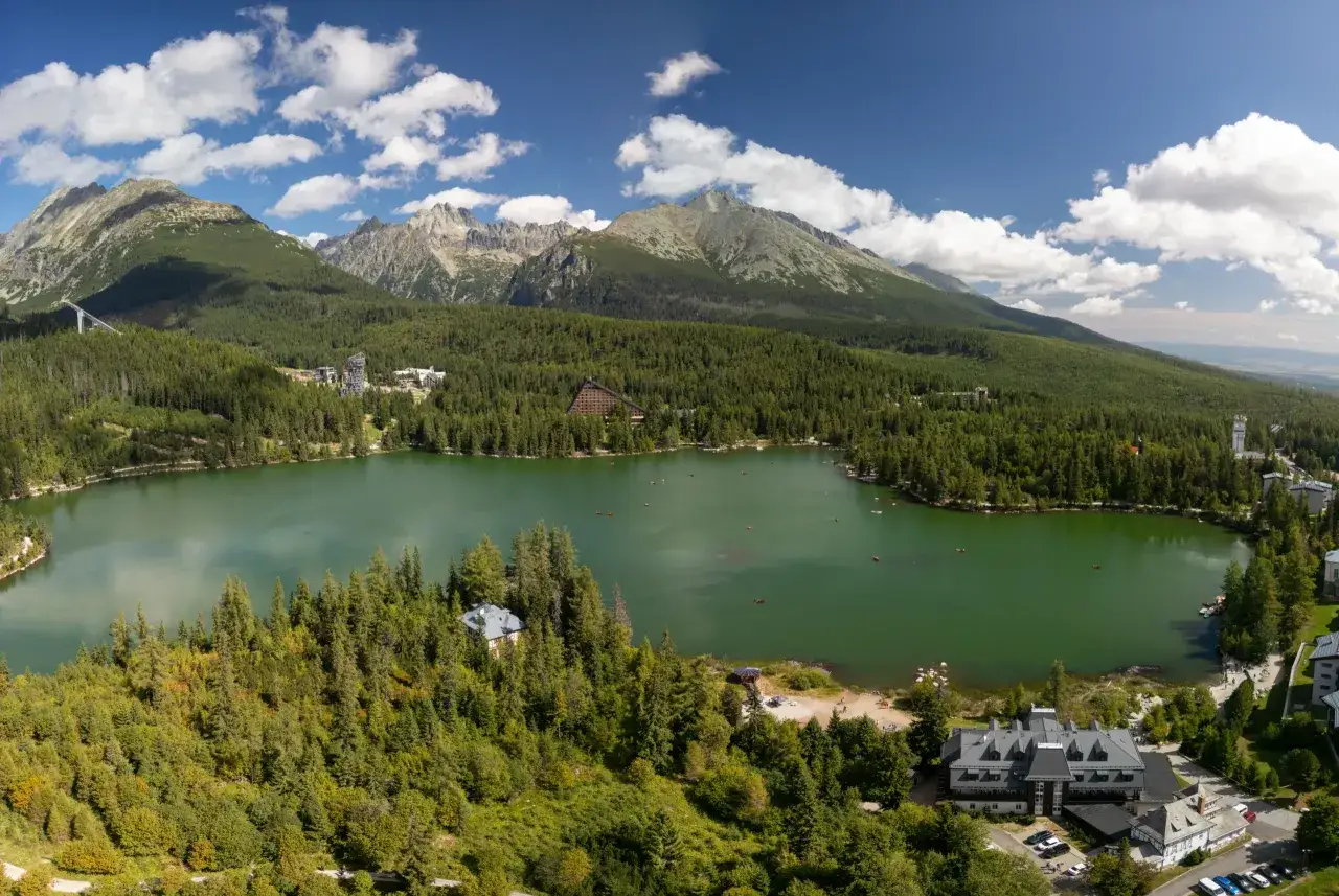 Idealne wakacje na Słowacji, gdzie góry spotykają się z jeziorem. Widok na Tatry Wysokie, lasy i turystów pływających łódkami.