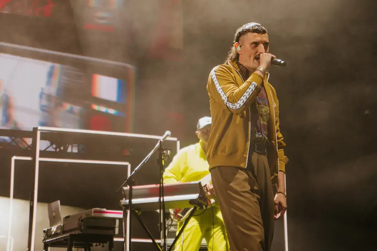 Dawid Podsiadło śpiewa na scenie, a obok niego klawiszowiec w żółtym dresie. Bardzo tekst, bardzo koncert!