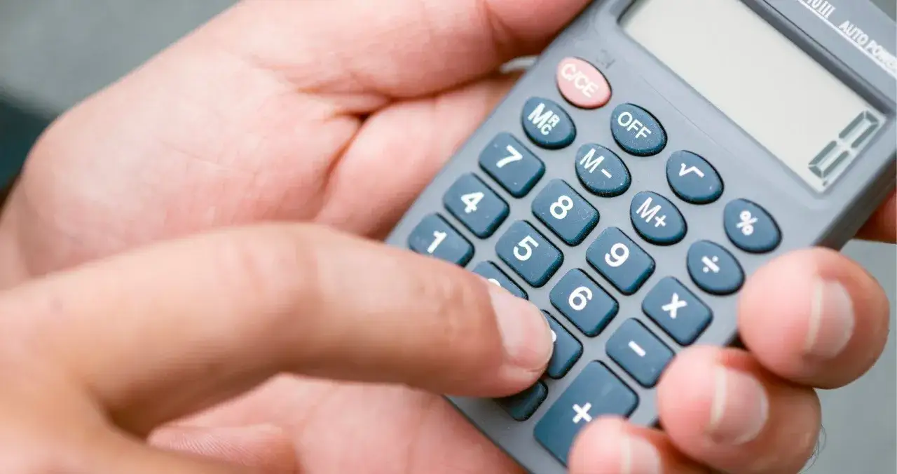 Dłoń z kalkulatorem, palec naciska klawisz. Pomaga to w zrozumieniu, jak obliczyć punkty do liceum.