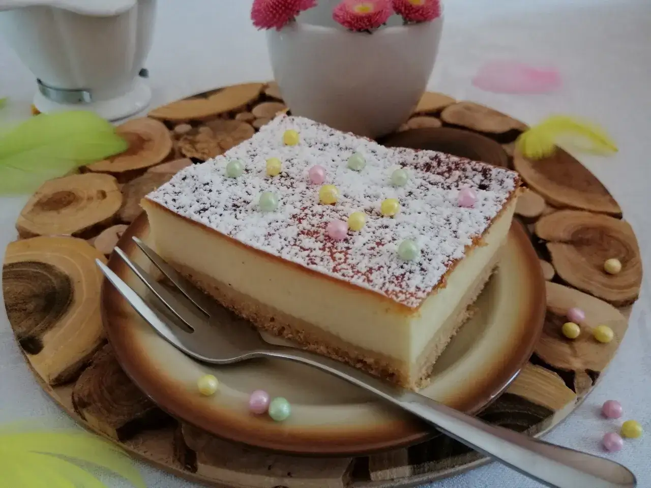 Pyszny sernik z cukrem pudrem i kolorowymi drażetkami, gotowy do podania.