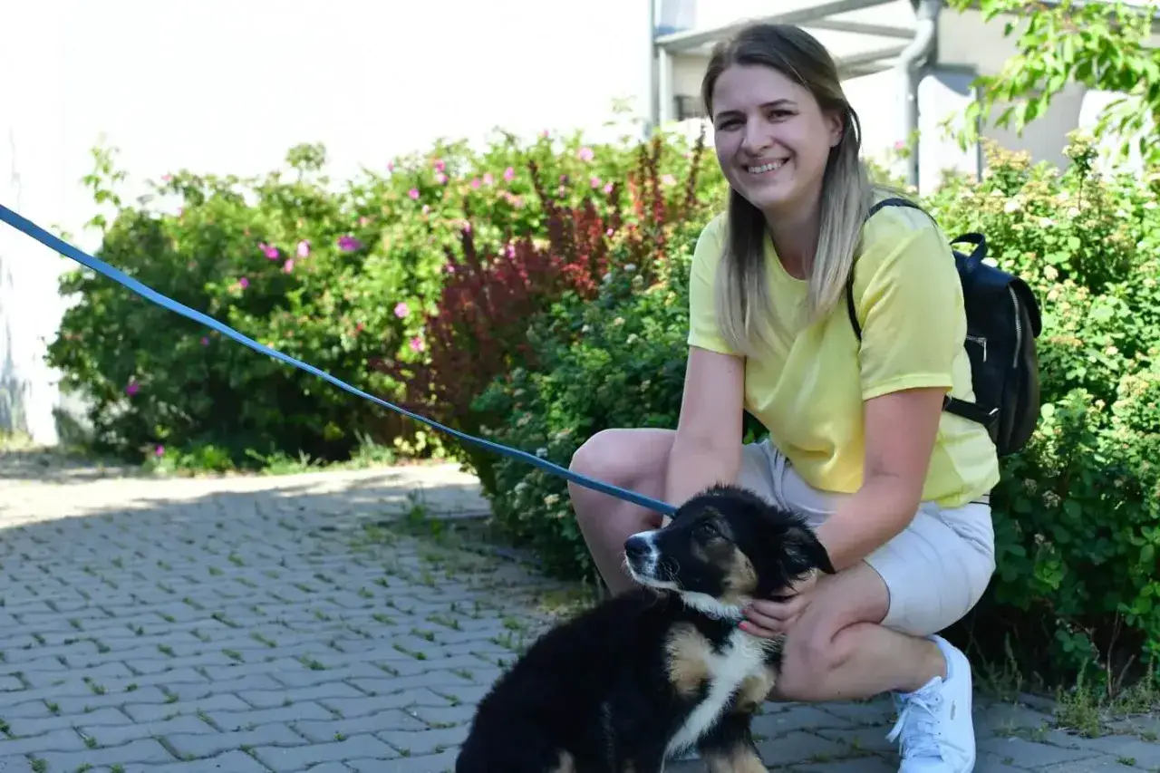 Uśmiechnięta dziewczyna z pieskiem na smyczy. Może to być inspiracja, jak nam&oacute;wić rodzic&oacute;w na psa.