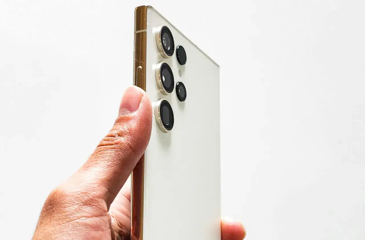 Biały Samsung S26 z wieloma obiektywami aparatów, gotowy na premierę. Złote wykończenie dodaje elegancji.