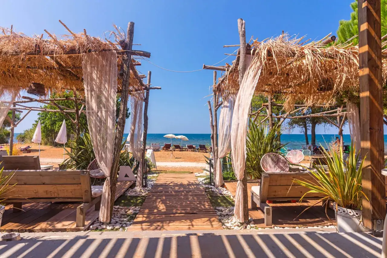 Drewniane ławki i ścieżka prowadząca na plażę w Chorwacji. Idealne miejsce na relaks, zastanawiasz się, ile kosztuje kemping w Chorwacji?