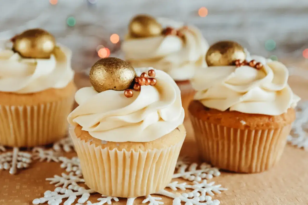 Puszyste muffinki z kremem i złotymi kulkami, idealne na święta. Ten przepis na wilgotne i puszyste muffinki zachwyci każdego!