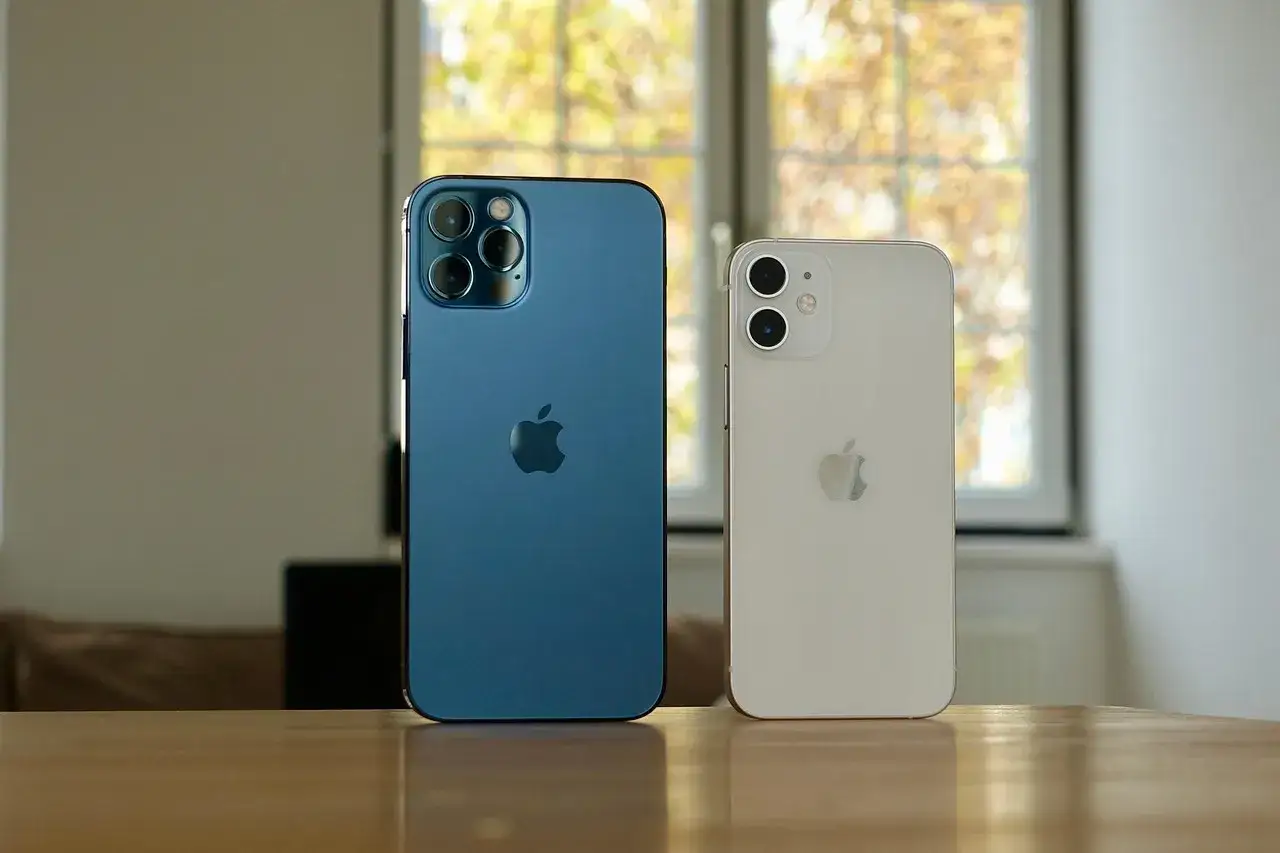 Dwa iPhone'y, niebieski i biały, na stole. Czy folia ochronna na telefon jest warta swojej ceny?