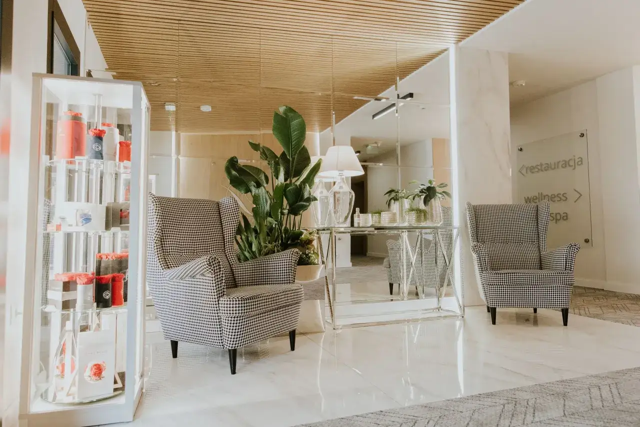 Eleganckie fotele i witryna z produktami hotelowymi. Hotel oferuje usługi uzupełniające, takie jak restauracja i spa.