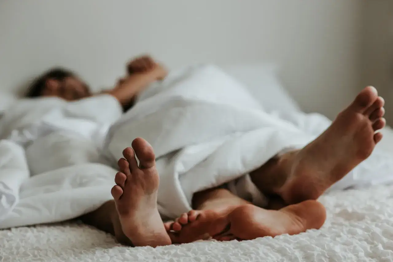 Stopy pary pod kołdrą. Czasem parcie na mocz podczas stosunku może być uciążliwe.