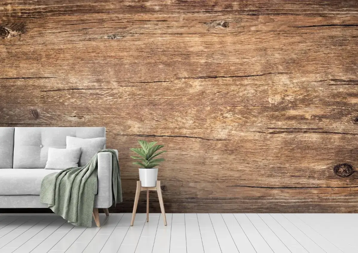 Przytulna szara sofa z zielonym kocem i rośliną na tle tapety ze starych desek.