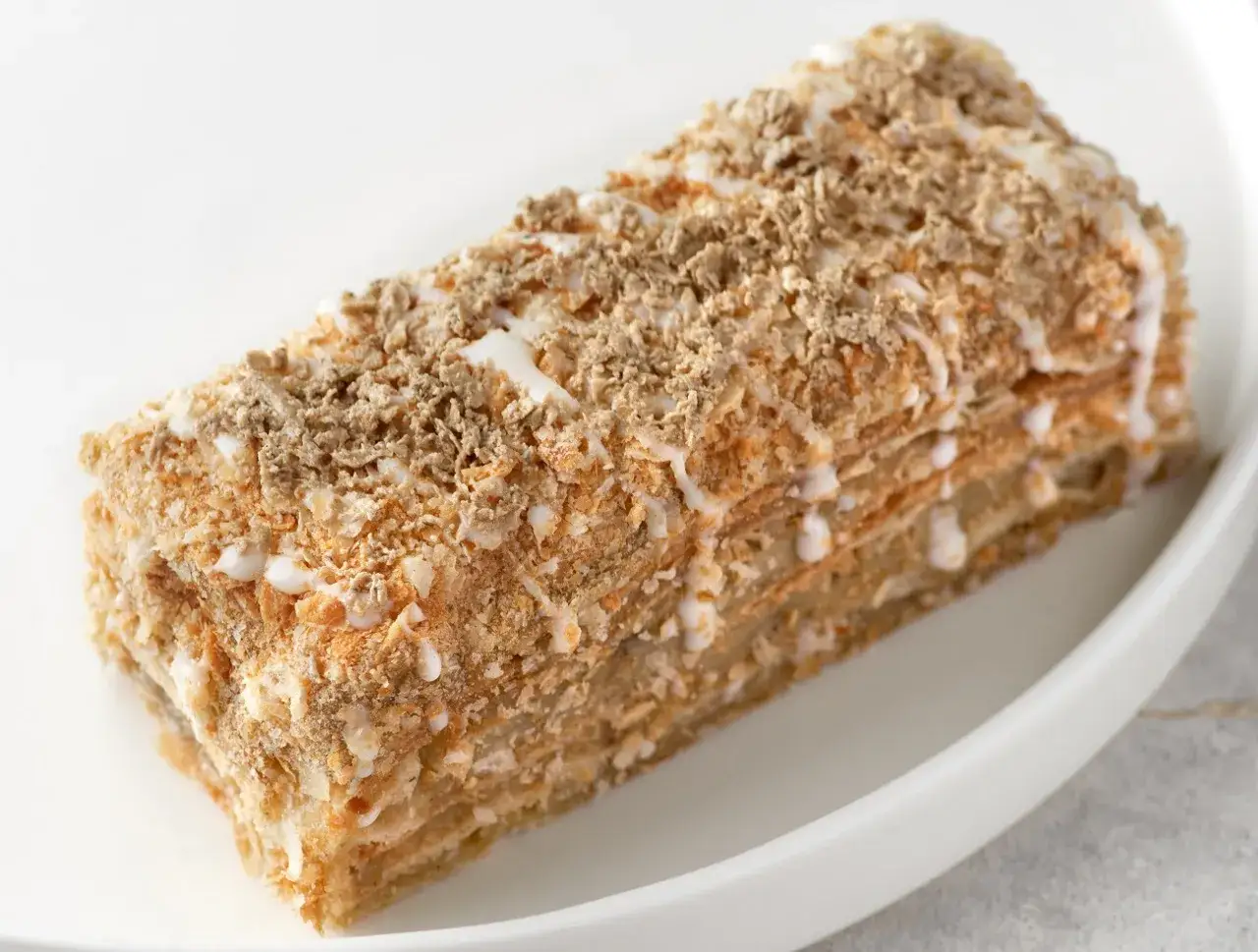 Pyszne ciasto z warstwami ciasta francuskiego i kremem chałwowym, posypane kruszonką. Idealne na deser, gdy szukasz inspiracji na przepis na ciasto z masą chałwową.