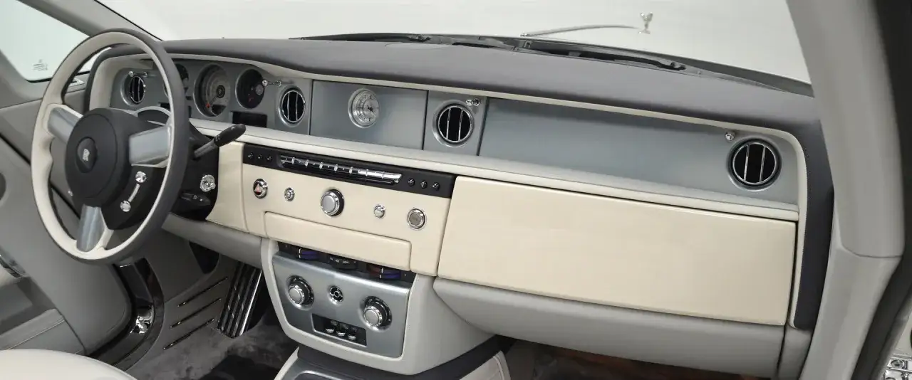 Wnętrze Rolls-Royce Phantom Drophead Coupe: kierownica, deska rozdzielcza z kremowymi panelami, zegar i chromowane detale.
