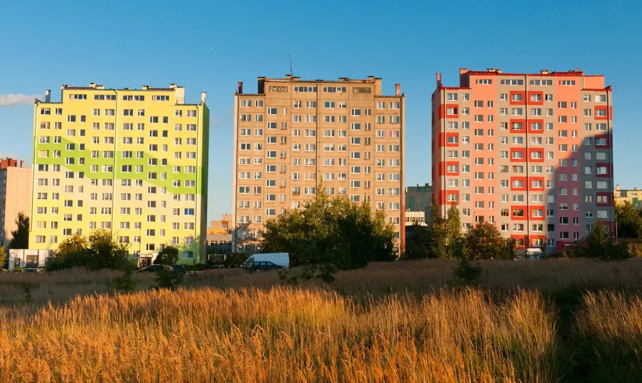 Kolorowe bloki mieszkalne na tle nieba. W tle widać samochody i drzewa. Podatek od nieruchomości Warszawa.