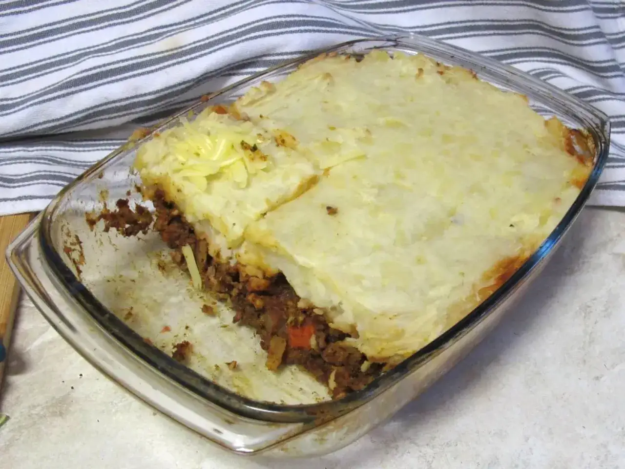 Zapiekanka pasterska (Shepherd's Pie) z warstwą mięsa mielonego i ziemniaków, posypana serem.