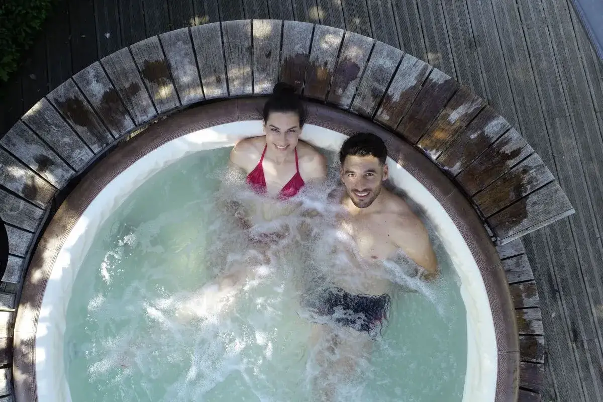 Para, uśmiechnięta para cieszy się gorącą kąpielą w jacuzzi. Idealny romantyczny weekend dla dwojga nad morzem.