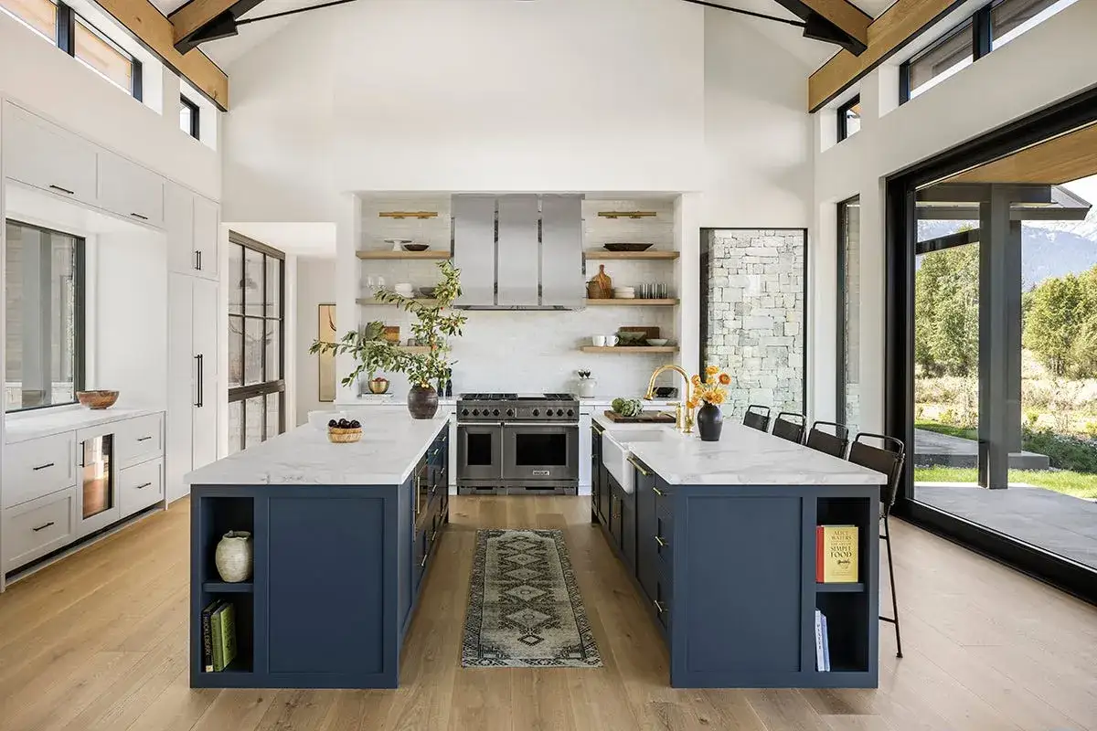 Cocina moderna con dos islas centrales de mueble de cocina, encimeras de mármol y armarios azules.