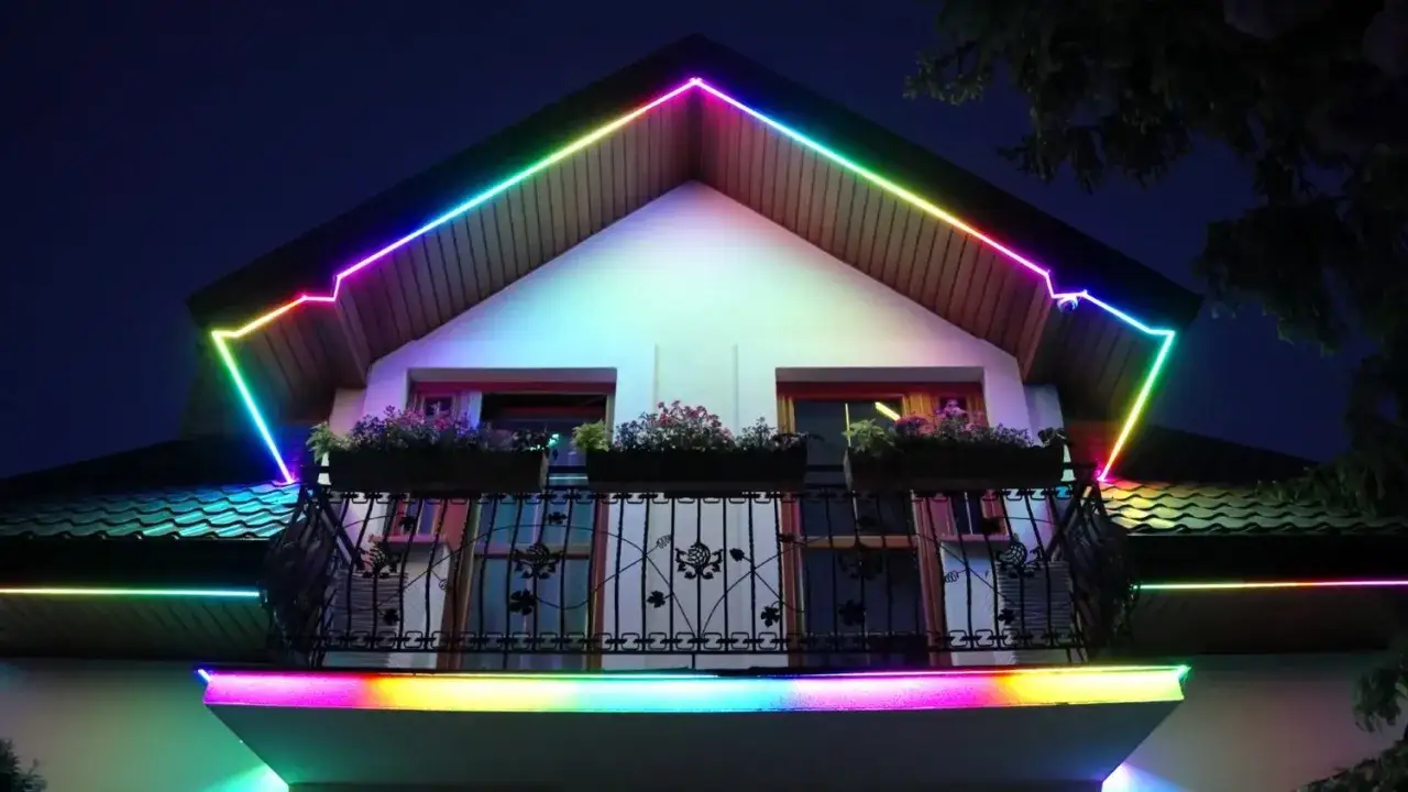 Kolorowy montaż taśmy LED na zewnątrz domu, podkreślający architekturę dachu i balkon.