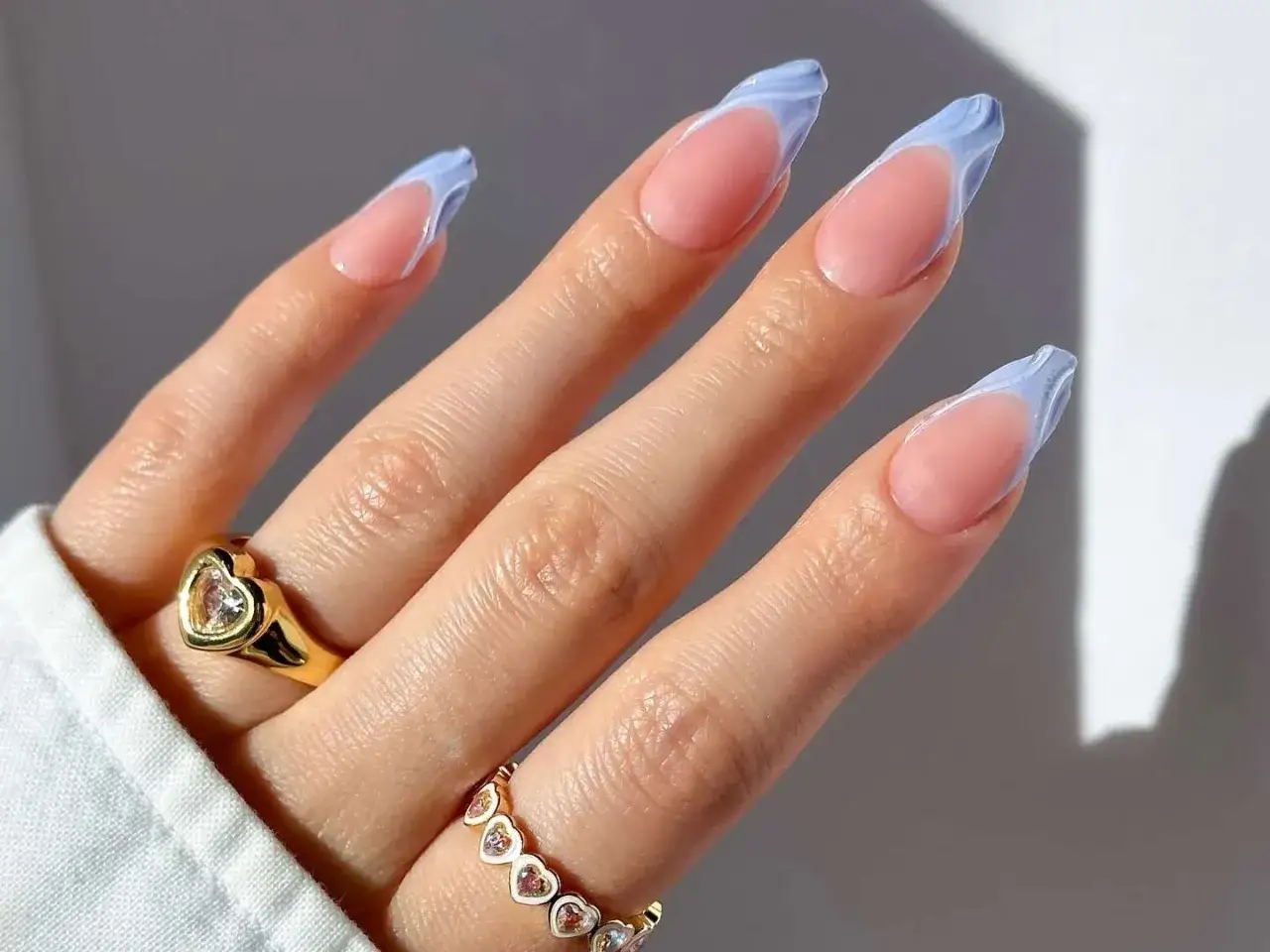 Dłoń z paznokciami w stylu francuskiego manicure z błękitnymi, falowanymi końc&oacute;wkami. R&oacute;żne rodzaje tips&oacute;w pozwalają na kreatywne zdobienia.