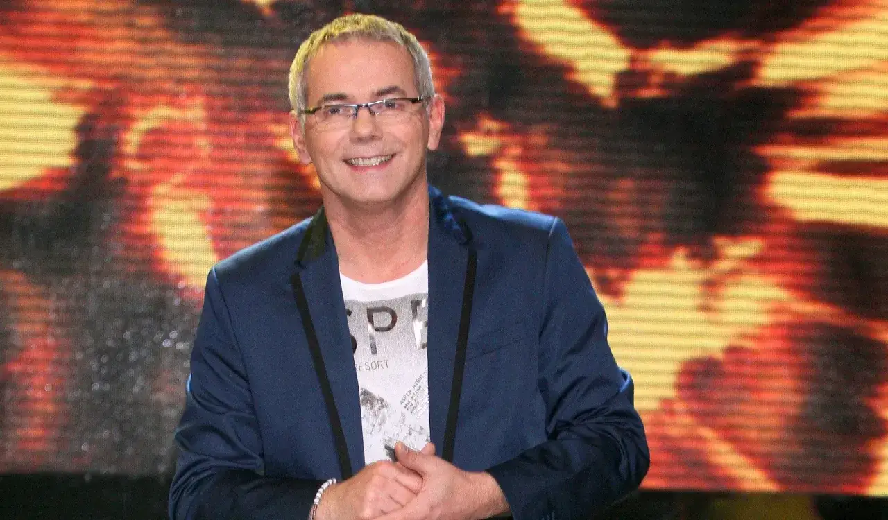 Robert Janowski uśmiecha się na tle płonącej scenografii, a widzowie zastanawiają się, dlaczego Robert Janowski naprawdę odszedł z Jaka to melodia po latach.