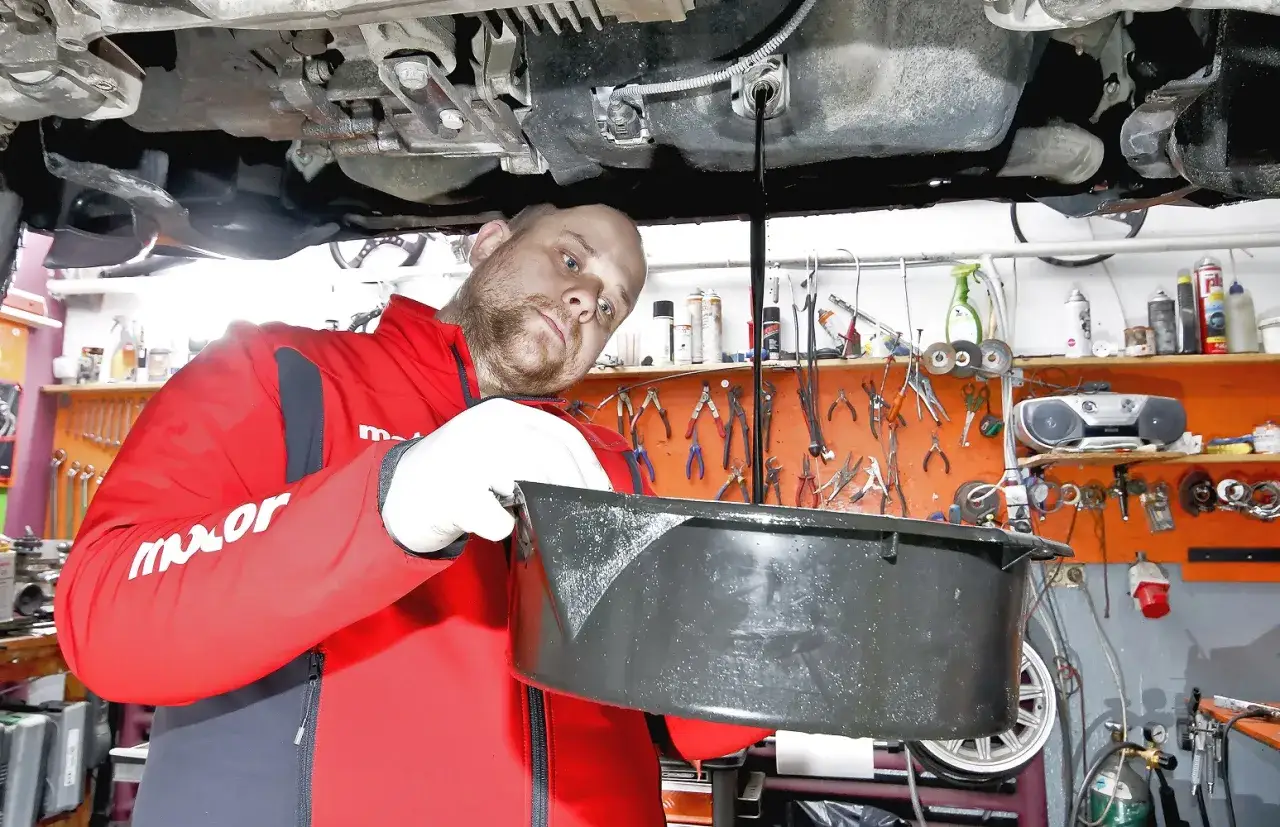 Mechanik wymienia olej w samochodzie. Zastanawiasz się, ile za wymianę oleju i filtrów?