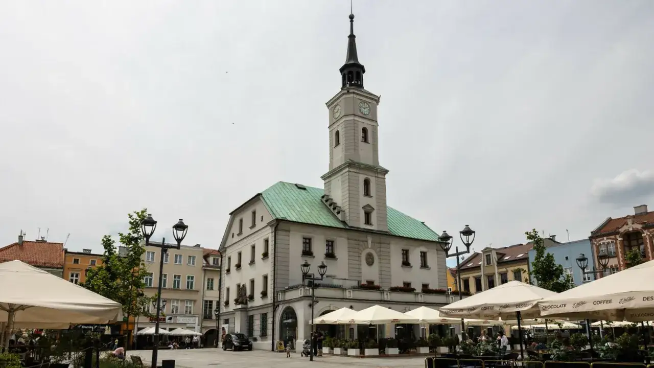 Rynek w Gliwicach z ratuszem i kawiarnianymi ogr&oacute;dkami pod parasolami.