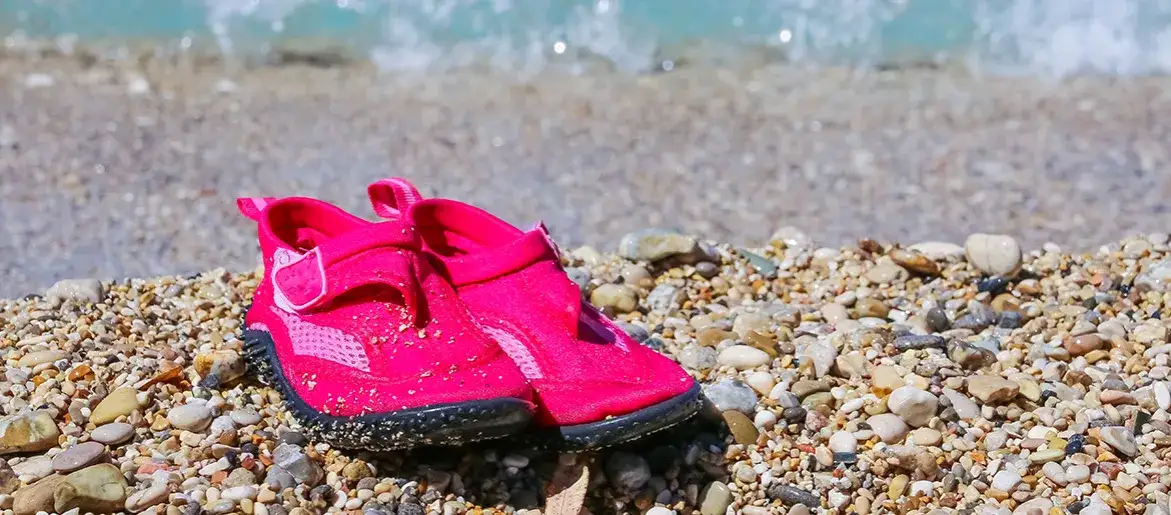 kamienista plaża w Chorwacji z dziećmi w butach do wody