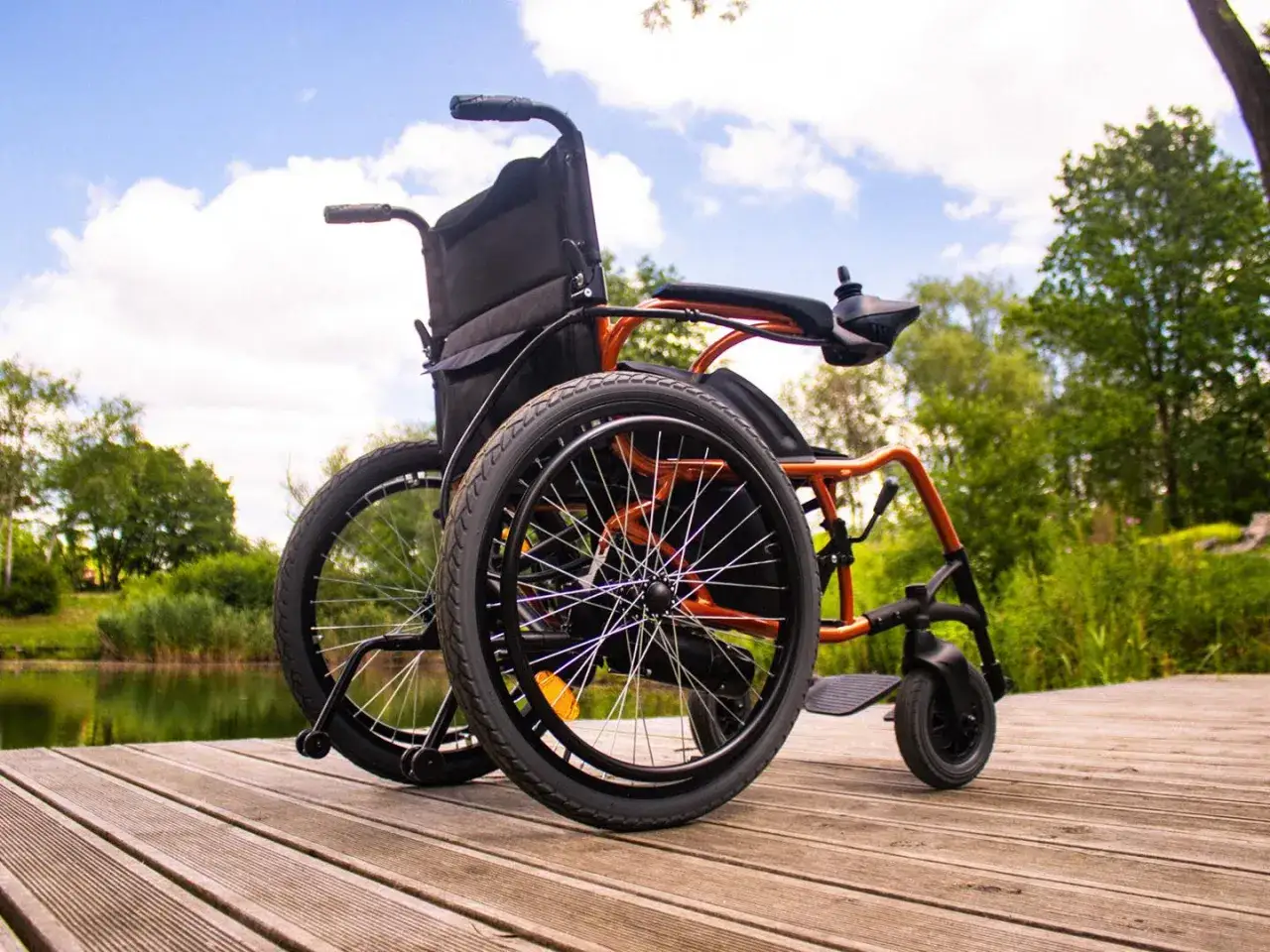 Wózek inwalidzki na drewnianym pomoście nad jeziorem. Czy można wypożyczyć taki wózek na wakacje?