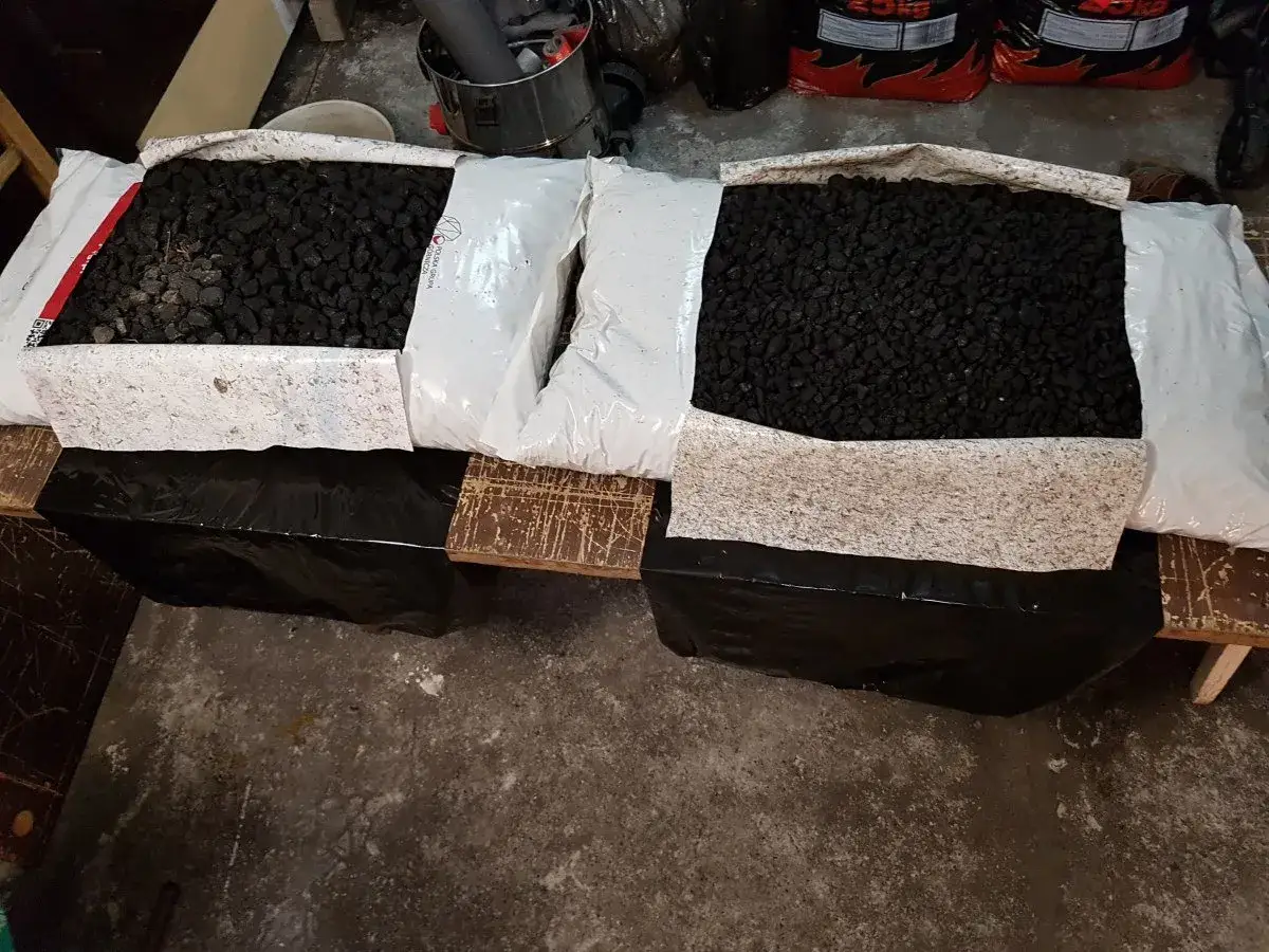 Dwa worki z ekogroszkiem leżą na drewnianej palecie. Widać, jak wysuszyć ekogroszek w workach, rozkładając go na palecie.