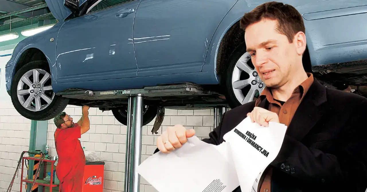 Mężczyzna w garniturze analizuje książkę serwisową i gwarancyjną auta na podnośniku. Warto wiedzieć, o co pytać przy zakupie auta.