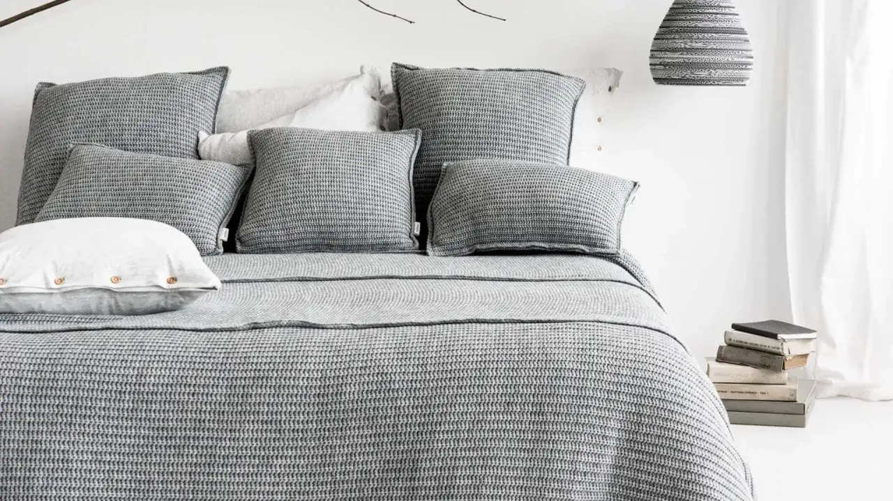 szara sypialnia różne tekstury poduszki pledy