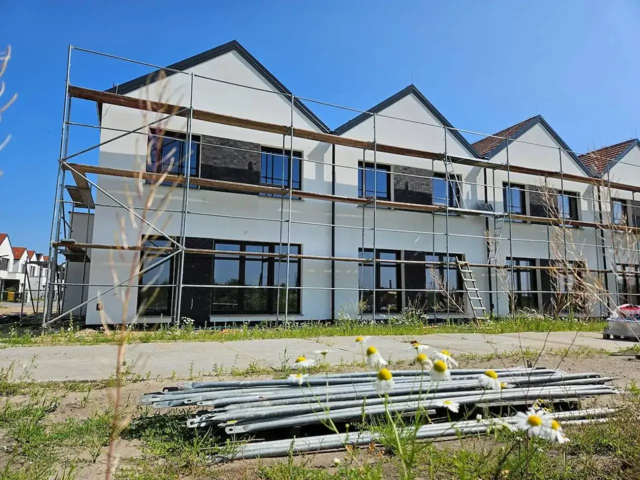 Nowy dom w budowie, otoczony rusztowaniami. Zastanawiasz się, czy kupując dom od dewelopera, płacisz podatek?