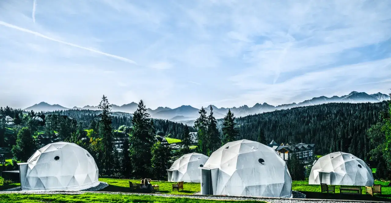 Nowoczesny pole namiotowe Bukowina Tatrzańska z kopułami i widokiem na g&oacute;ry.