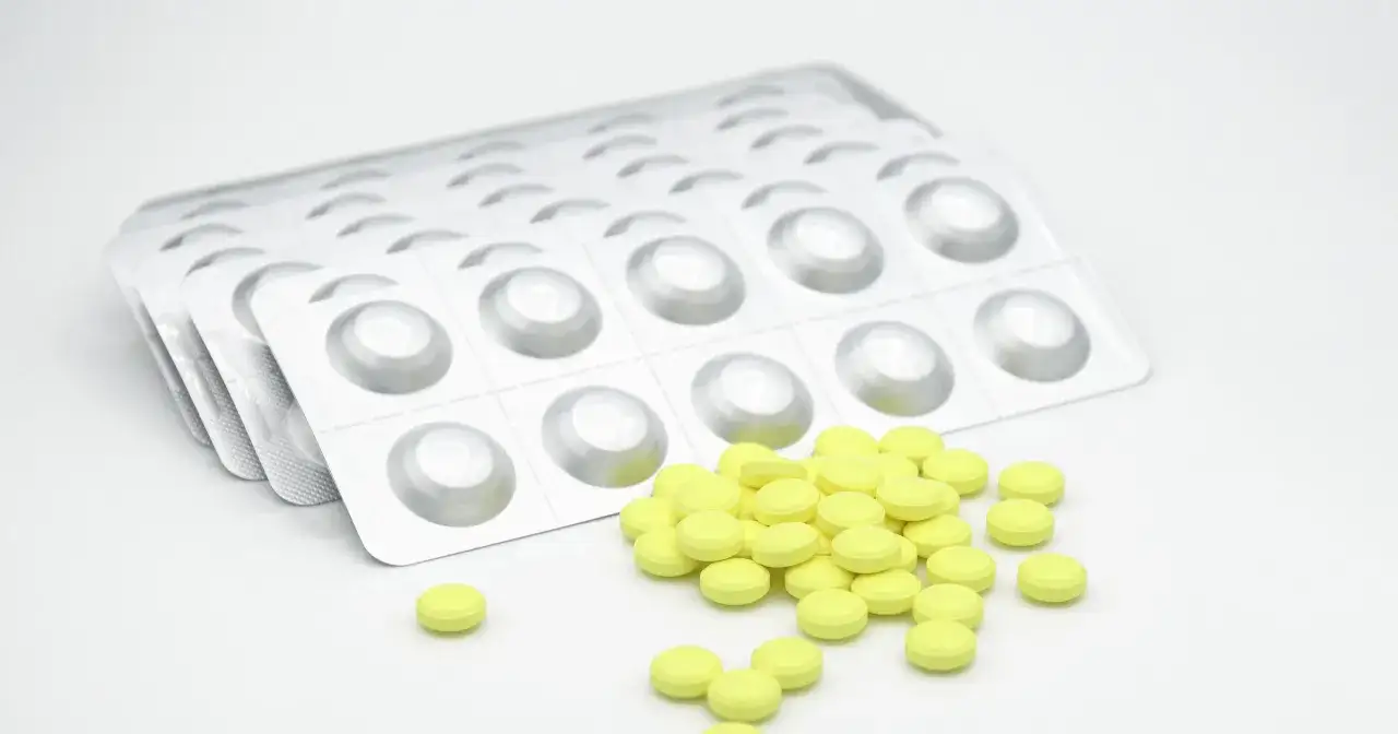 Opakowania leku i rozsypane żółte tabletki. Informacje o persen forte dawkowanie.