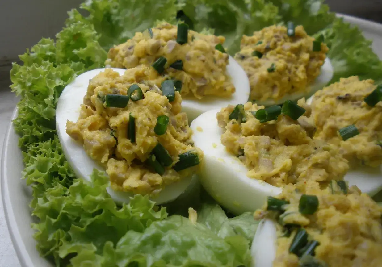 Pyszne jajka faszerowane pieczarkami i szczypiorkiem, podane na liściach sałaty. Idealna przekąska na każdą okazję.
