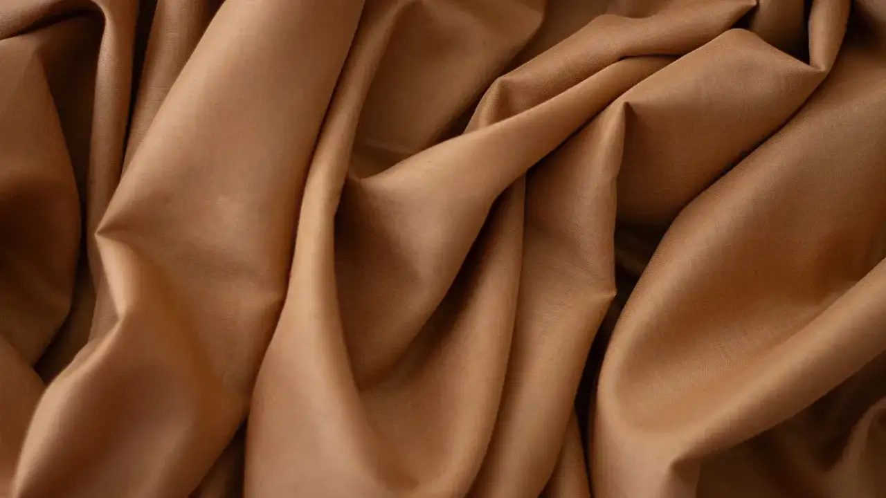 Gładka, brązowa krepa układa się w miękkie fałdy. To materiał, kt&oacute;ry nadaje się do szycia eleganckich ubrań.