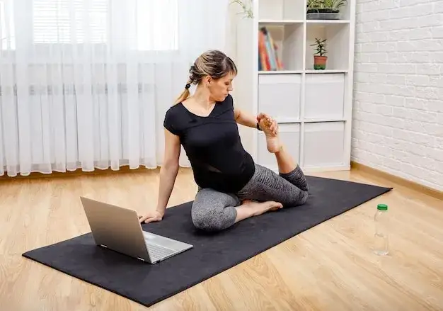 kobieta ćwicząca jogę w domu przed laptopem