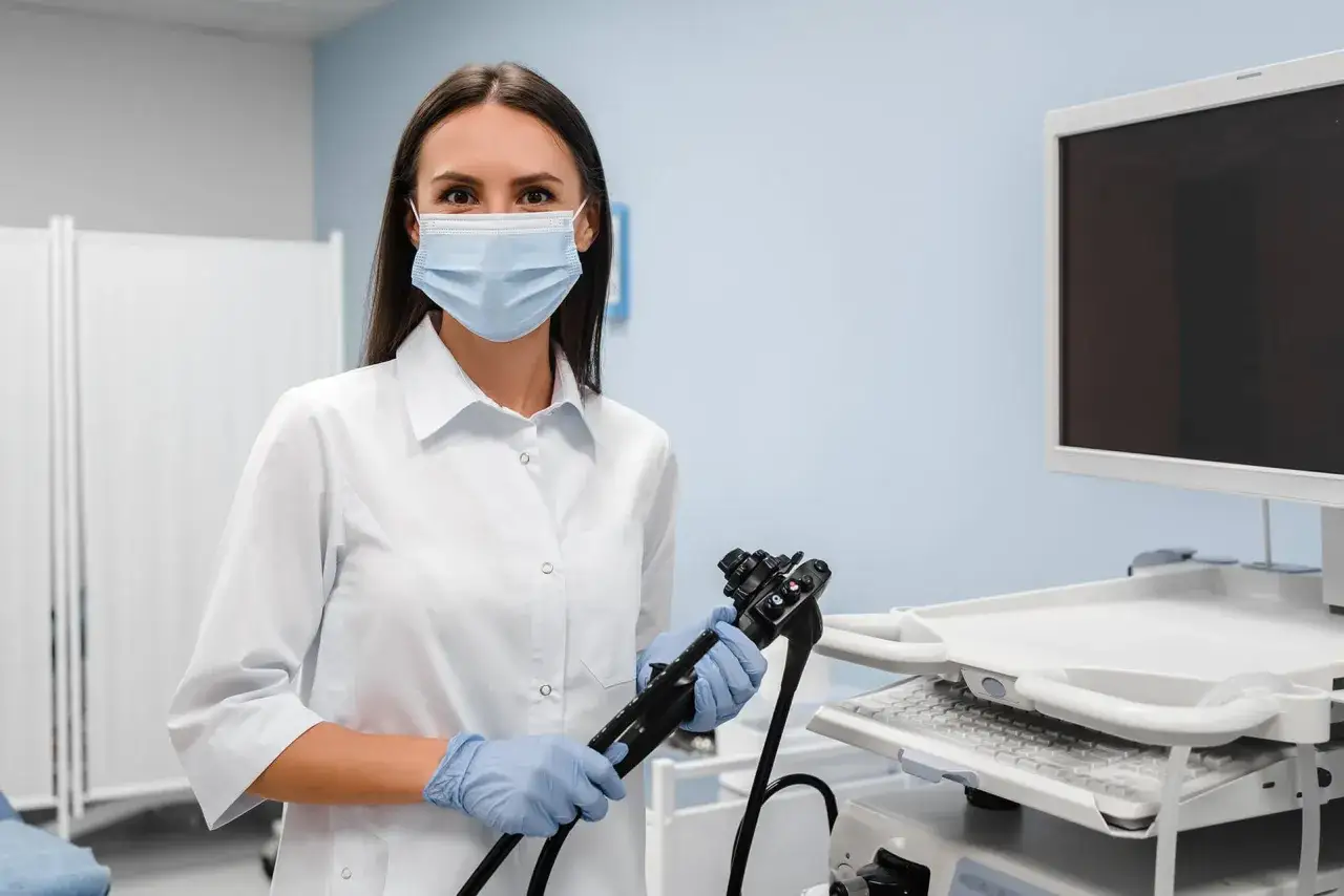 Lekarka w masce i rękawiczkach trzyma gastroskop. Pytanie: czy przed gastroskopią można brać leki?