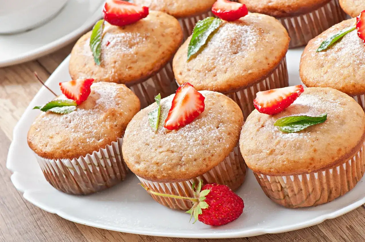Słodkie muffinki z truskawkami i miętą, posypane cukrem pudrem, z delikatną polewą z serka mascarpone.