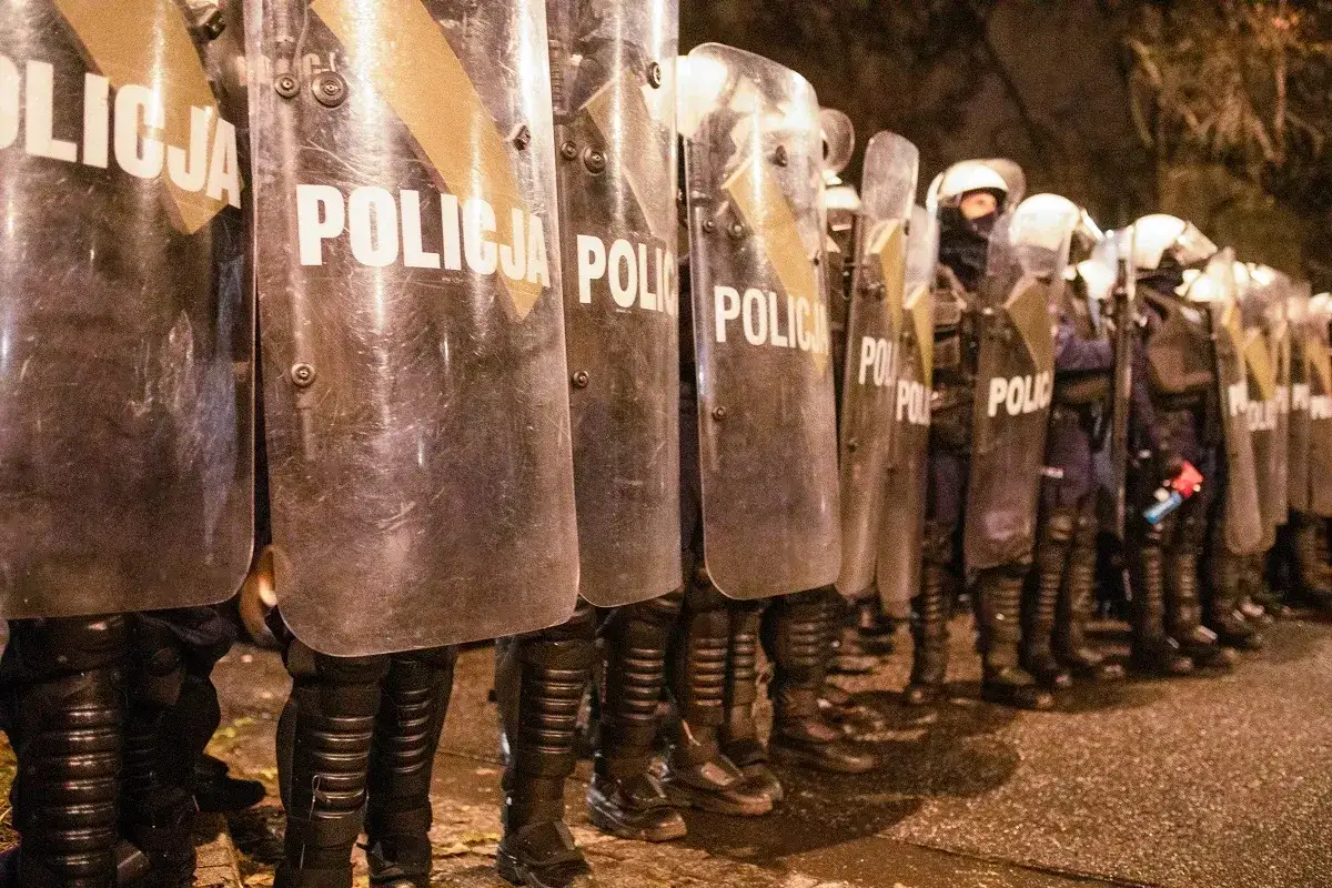 Policja w pełnym rynsztunku, z tarczami i pałkami, gotowa do działania. Wyglądają jakby panował stan wyjątkowy.